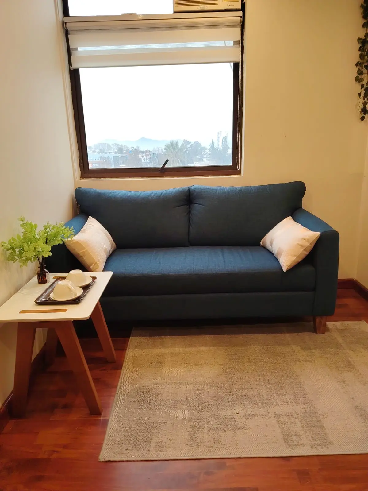 Sala de espera de Punto Salud Consciente con sofá azul, ventana y mesa auxiliar